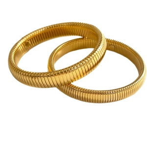 Set of two gold-colored textured bangle bracelets with vintage snake pattern on white background