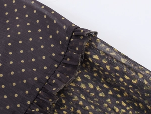 Close-up of lightweight black chiffon fabric with yellow polka dots and ruffle details
