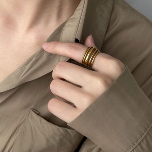 Close-up of a layered gold ring with a minimalist multi-band winding design on a finger