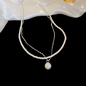 Détail du collier double couche plaqué or avec perles et pendentif élégant