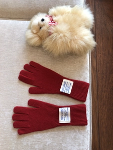 Detalle de guantes de punto de lana roja con etiquetas blancas y función táctil