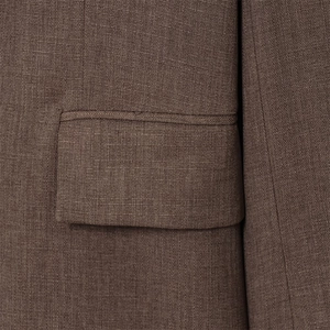 Gros plan sur la texture tissée et le détail de la poche d'une veste de costume marron