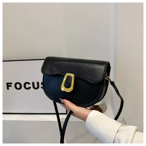 Close-up of black leather saddle bag with gold geometric buckle and long shoulder strap