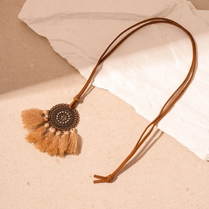 Detail of bronze floral medallion pendant with long tassels on a bohemian sweater chain