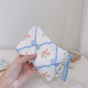 Detailed shot of blue ribbon and floral print on cotton pouch with a rope zipper puller
