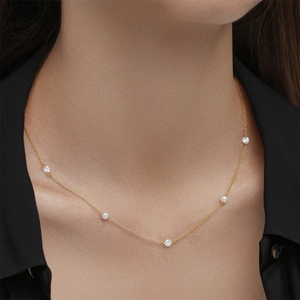 Detail of a gold plated Y-shape necklace with fresh water pearls and sparkling rhinestones