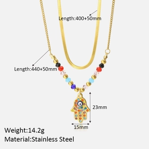 Detailed specs of layered gold necklace with Hamsa hand and evil eye pendant charms