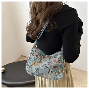 Close-up of floral jacquard hobo bag featuring blue embroidery and adjustable strap