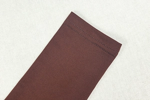 Close-up of dark brown knitted fabric showing professional double-stitch sewing detail
