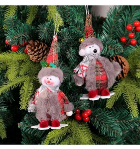 Detail of plush snowman and bear Christmas ornaments hanging on a festive tree branch