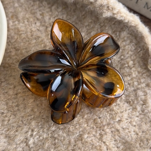 Macro shot of an amber flower hair claw clip on beige plush fabric background