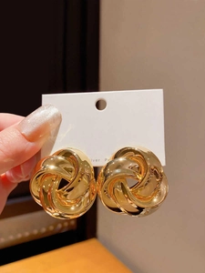 Detail of twisted gold layered hoop earrings with silver posts and metallic shine