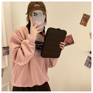Quilted black laptop sleeve shown in a lifestyle mirror selfie with casual streetwear