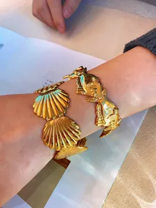Detail of vintage gold-plated shell and fish bangle set on a female wrist in daily life