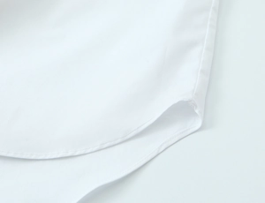 Close-up of curved hemline and precise stitching on white button-up shirt for women
