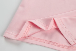 Gros plan sur l'ourlet de la robe en tricot rose avec coutures à double aiguille
