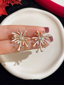 Macro shot of firework-shaped gold earring with heart-shaped crystal and white enamel