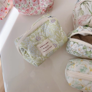 Close-up of quilted floral cotton makeup bags with zippers in pink and green patterns