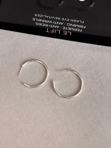 Polished silver C-shaped hoop earrings on a textured grey background with prop