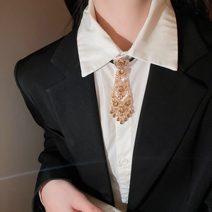 Close-up of gold tie-style tassel necklace with amber crystals on a black suit blazer