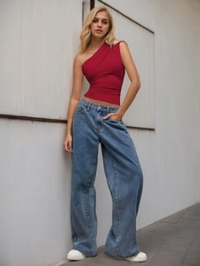 Chic red one-shoulder ruched slim top paired with blue wide-leg jeans in a street style view