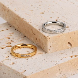 Polished gold and silver minimalist rings with diagonal zircon stones on stone background