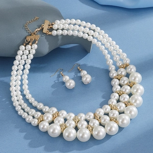 Close-up of multi-layer pearl necklace and matching earrings on blue textured surface