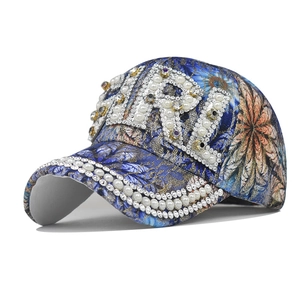 Detail of blue floral baseball cap featuring pearl and rhinestone GIRL embroidery