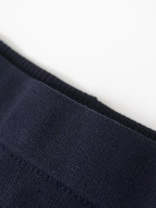 Detailed macro view of dark blue knit fabric showing refined sewing and edge texture