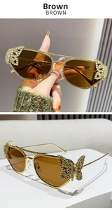 Detail of gold metal sunglasses with crystal butterfly decor and brown lenses