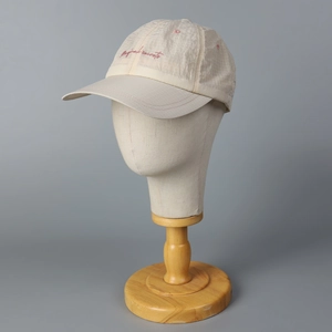 Beige checkered quick-dry baseball cap with red embroidered letters on wooden stand