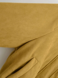 Detailaufnahme der senfgelben Wildledertextur und der seitlichen Taschennaht des Jackets