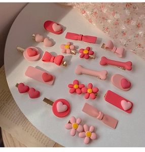 Flat lay of 15 pieces pink resin heart and flower hair clips set on a decorative plate