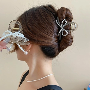 Elegant acrylic bow hair claw with pearls for women shown in a stylish updo hairstyle