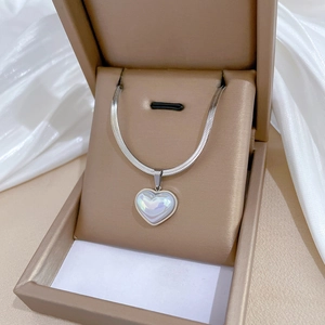 Detailed view of iridescent heart pendant on silver snake chain inside a premium box