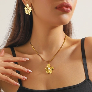 Close-up of gold-plated flower necklace and earrings set with pearl centers on a model