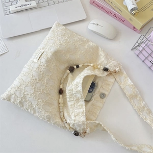 Detail of floral lace tote bag with marble beads and interior pocket on desk