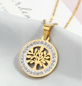 Detail shot of a golden tree of life pendant with crystals on grey satin fabric