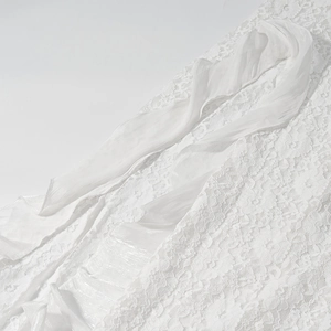 Détail de la dentelle blanche et des volants en tulle transparent sur la robe