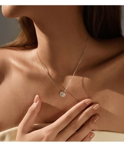 Close-up of a silver D-color moissanite halo pendant necklace on model neckline
