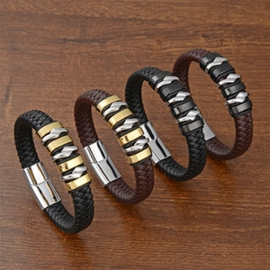 Detail of four multi-layer braided leather bracelets with metallic magnetic clasps on wood