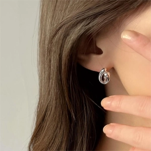 Detail view of a 925 silver curved earring worn by a model in minimalist style