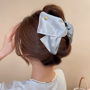 Detail of light blue satin bow hair claw with gold handmade engraved metal tag