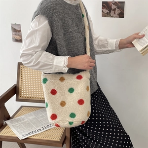 Close-up of plush shoulder bag with colorful polka dots on a soft faux fur material
