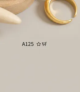 Detail of golden crescent ring on textured stone and wood, highlighting smooth metal finish
