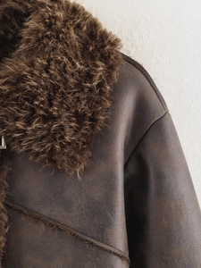 Close-up of dark brown leather jacket featuring thick faux fur collar and textured leather
