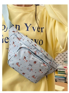 Detail of light blue crossbody bag with cartoon dachshund print worn by a model