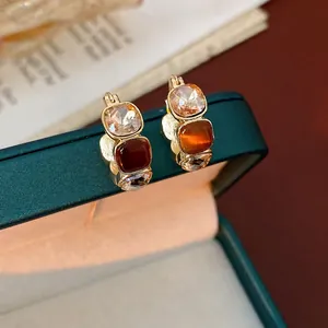Vintage gold U-shaped hoop earrings with three-color square crystals on green velvet