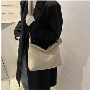 Detailed close-up of a minimalist beige large capacity crossbody bag with silver zipper