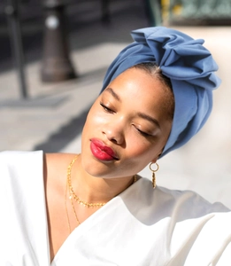 Detail of blue French vintage turban hat on a model with elegant gold accessories